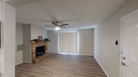 This single-floor residence offers a clean, updated interior with a cohesive neutral palette and durable wood-look flooring that runs throughout the entire space. The living room serves as the heart of the home, anchored by a classic brick fireplace with a wood mantle and complemented by a ceiling fan with integrated lighting. Vertical blinds cover a large sliding door, allowing natural light to filter in while providing privacy. The entry opens directly into this welcoming living area, creating an immediately open and airy feel.

The galley-style kitchen is efficiently designed with ample white shaker cabinetry, granite-look countertops, a stainless steel sink, and modern hardware. A full-size refrigerator and dishwasher are included, making the space fully functional.

The bedrooms are well-sized, each featuring ceiling fans, neutral walls, wood-look flooring, and window blinds that admit natural light. The textured ceilings add subtle depth to each room.

Two bathrooms mirror the kitchen's aesthetic with white cabinetry, granite-topped vanities, and updated fixtures. Upper cabinets provide additional storage, while large mirrors and bright vanity lighting enhance each bathroom's utility. The overall design is practical, consistent, and move-in ready.