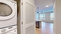 Located at 4200 N Carlin Springs Rd in Arlington, Virginia, this efficiently designed unit offers a well-considered layout that maximizes every square foot across a single floor. Light-toned hardwood-style flooring runs throughout the living areas, complementing the clean white walls and creating a bright, cohesive aesthetic. Large windows dressed with horizontal blinds allow generous natural light to fill the space while framing views of the surrounding Arlington urban landscape.

The modern kitchen serves as a functional centerpiece, featuring sleek gray flat-front cabinetry, a white subway tile backsplash, and a full suite of stainless steel appliances including a French door refrigerator, electric range, and over-the-range microwave. A peninsula with a crisp white quartz countertop and an integrated sink with a matte black spring-neck faucet provides additional prep space and a natural transition into the living area, accented by stylish pendant lighting overhead.

The bathroom is finished with large-format light tile, a soaking tub with shower, and matte black fixtures that add a contemporary touch. A dedicated in-unit laundry closet houses a stacked washer and dryer for added convenience. Two closets provide practical storage, while a ceiling fan with light in the main living area enhances comfort year-round.