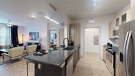 This well-designed single-floor residence showcases a thoughtful open-concept layout that seamlessly connects the kitchen, dining, and living areas. The kitchen serves as a focal point, featuring a large dark granite island with bar seating, two-tone cabinetry in warm wood tones, stainless steel appliances, a decorative tile backsplash, and modern pendant and track lighting overhead. Light wood-style flooring flows throughout the common areas, creating a bright and cohesive aesthetic.

The living room offers a comfortable retreat with a ceiling fan, large windows dressed in floor-to-ceiling drapes that invite natural light, and ample space for relaxed seating arrangements.

The primary bedroom is generously sized with plush carpeting, multiple windows with blinds and drapes, and a ceiling fan, providing a calm and restful atmosphere. A spacious walk-in closet with built-in shelving and hanging rods adds excellent storage. The second bedroom mirrors the comfort of the primary with its own large window, ceiling fan, and soft carpeting.

The bathroom is finished with classic white subway tile surrounding the tub-shower combination, wood-look flooring, and a granite-topped vanity with wood cabinetry, tying together the home's modern and clean design sensibility.
