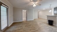 Located at 350 Joshua Pl NW in Concord, NC, this single-story, four-bedroom, two-bathroom home offers a practical and comfortable layout. The living room features warm wood-look luxury vinyl flooring, crown molding, a ceiling fan, and natural light streaming through windows with horizontal blinds, creating a bright and welcoming atmosphere. The kitchen is well-appointed with gray shaker-style cabinetry, granite-look countertops, stainless steel appliances including a refrigerator, range, microwave, and dishwasher, all complemented by light wood-look flooring. The four bedrooms are finished with neutral carpet and ceiling fans, providing a cozy and restful environment. The primary bathroom includes a walk-in shower with built-in shelving and brushed nickel fixtures, while the secondary bathroom offers a full soaking tub and shower combination. A dedicated laundry room with wood-look flooring includes a washer and dryer alongside a built-in wire shelving closet for added storage. Three closets throughout the home provide ample storage solutions. Neutral warm tones and consistent finishes across the home contribute to a clean, cohesive aesthetic throughout.