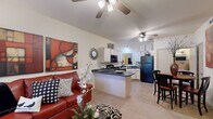 This single-story, one-bedroom, one-bathroom residence offers a thoughtfully designed layout that maximizes functionality and comfort. The open-concept living and kitchen area forms the heart of the home, featuring vaulted ceilings with ceiling fans that enhance the sense of airiness throughout. The kitchen is equipped with dark granite-style countertops, white cabinetry, black appliances including a refrigerator, range, microwave, and dishwasher, and a peninsula that provides additional prep space and casual seating. Tile flooring extends through the kitchen and dining area, while the living room transitions to plush carpet, creating a warm and inviting atmosphere. Large windows with horizontal blinds allow natural light to fill the living space. The bedroom is generously sized, featuring carpet flooring, a ceiling fan, and a window overlooking the exterior. It is complemented by a walk-in closet outfitted with wire shelving for ample storage. The full bathroom includes a vanity with white cabinetry, a large mirror with overhead lighting, and tile flooring. A dedicated in-unit laundry closet adds everyday convenience to this efficiently designed residence.