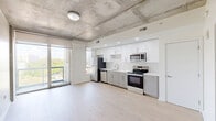 Located at 1901 Callowhill Street in Philadelphia's Callowhill neighborhood, this one-bedroom, one-bathroom residence offers a thoughtfully designed layout across a single floor. The unit blends industrial character with modern finishes, most notably through its exposed concrete ceilings and structural columns that lend an urban loft aesthetic throughout the living spaces.

Light-toned hardwood flooring runs continuously through the main areas, enhancing the sense of openness. The kitchen is well-appointed with two-tone cabinetry — white upper cabinets paired with gray lowers — a white subway tile backsplash, quartz countertops, and a full suite of stainless steel appliances including a refrigerator, dishwasher, range, and over-the-range microwave. Recessed lighting illuminates the space efficiently.

The bedroom features the same exposed concrete ceiling and a horizontal clerestory window that brings in natural light while maintaining privacy. A sliding door and dedicated closet add functional storage.

The bathroom is finished with large-format gray floor tiles and marble-look wall surround in the tub/shower combination, creating a clean, contemporary feel.

A private balcony offers open views of the Philadelphia skyline and surrounding neighborhood, providing an inviting outdoor retreat. The unit also includes a hallway and additional unclassified space, completing a well-rounded and functional floor plan.