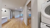 This thoughtfully designed 2-bedroom, 2-bathroom residence at 51 Okner Pkwy in Livingston, NJ offers a clean, modern aesthetic across a single floor. Light wood-tone flooring flows seamlessly throughout, complementing the neutral gray palette and recessed lighting found in every room.

The open-concept kitchen is a standout, showcasing floor-to-ceiling dark cabinetry with brushed gold hardware, crisp white quartz countertops, a vertical tile backsplash, and a full suite of stainless steel appliances including a gas range and French door refrigerator. A large central island with pendant lighting anchors the space, which opens directly to the living area with access to a private balcony.

Both bedrooms are well-proportioned with natural light from large windows fitted with roller shades. The primary bedroom includes a spacious walk-in closet with built-in shelving and hanging systems. Four closets total provide generous storage throughout.

The primary bathroom features marble-look tile flooring, a dual-sink dark vanity with white quartz countertops, a large wall mirror, and a glass-enclosed walk-in shower with a rain showerhead. The second bathroom offers the same refined finishes with a tiled tub-shower combination. Additional conveniences include in-unit laundry and a dedicated utility room.