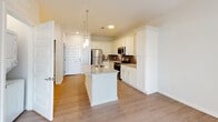 Located at 327 Guinevere Ln in Wilmington, NC, this single-floor home offers a thoughtfully designed layout with contemporary finishes throughout. The kitchen serves as a central highlight, featuring crisp white shaker cabinetry extending to the ceiling for ample storage, granite countertops, a subway tile backsplash in a classic gray tone, and a full suite of stainless steel appliances. A central island with a built-in sink and pendant lighting above adds both functionality and style, while light wood-tone flooring ties the space together seamlessly. The living area is bathed in natural light, with a glass-paned door opening directly to a private outdoor patio, offering views of the surrounding greenery. A ceiling fan overhead enhances comfort in this bright, airy space. The bedroom is finished with plush carpeting, a ceiling fan, and a window with outdoor views, creating a calm and comfortable retreat. The bathroom is well-appointed with a granite-topped vanity, white cabinetry, a large mirror, and a walk-in glass-enclosed shower, all set over warm wood-look flooring. Clean white walls and neutral tones throughout the home create a cohesive, modern aesthetic that is both welcoming and move-in ready.