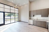 Located at 1446 Central Ave in Chattanooga, TN, this modern one-bedroom, one-bathroom unit offers a thoughtfully designed open-concept layout. The combined kitchen and living area is a standout feature, boasting impressively high ceilings and large floor-to-ceiling windows fitted with roller shades that flood the space with natural light. A sliding glass door opens directly onto a private balcony with metal railing, offering pleasant outdoor views. Light-toned hardwood-style flooring runs throughout, enhancing the bright, airy ambiance, while a ceiling fan adds both style and function.

The kitchen is well-appointed with taupe flat-front cabinetry, granite countertops, a gold-toned faucet, and a full suite of stainless steel appliances including a refrigerator, electric range, microwave, and dishwasher — providing ample storage and functionality.

The bedroom is a comfortable, private retreat, accompanied by a dedicated closet for storage. The bathroom features matching taupe cabinetry, granite countertops, a vessel sink, and a full bathtub and shower combination with tile surround. A dedicated laundry area completes the unit, offering added everyday convenience. The overall design is clean, contemporary, and efficiently organized.