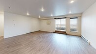 This single-floor unit presents a clean, modern aesthetic carried consistently throughout its well-organized layout. Wood-look flooring runs continuously across all rooms, lending warmth and visual cohesion to the space. The open living area is generously proportioned, featuring recessed lighting, baseboard heating, and large windows that frame outdoor views, filling the room with natural light and creating an airy atmosphere.

The kitchen is thoughtfully designed with warm wood cabinetry, stone-finish countertops, a stainless steel range with a sleek wall-mounted range hood, and a tiled backsplash in a cool blue-grey tone, adding a refined touch to the functional workspace. A stainless steel refrigerator completes the appliance lineup.

The bedrooms offer comfortable proportions, with ceiling fans, ample natural light, and varied window styles including a distinctive horizontal clerestory window in one room. At least one bedroom includes a spacious walk-in closet with wire shelving for organized storage.

The bathrooms are well-appointed, featuring wood-toned vanity cabinetry with a linen tower, a large mirror, and a walk-in shower with a built-in seat. Hallways connect the rooms in a logical, efficient flow, contributing to the unit's overall functional and understated design.