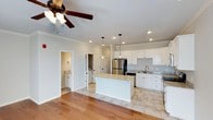 This well-appointed two-story townhouse offers three bedrooms, two and a half bathrooms, and an attached garage across a thoughtfully designed floor plan. The open-concept main level centers around a bright, modern kitchen featuring white shaker cabinetry, granite countertops, a center island, and stainless steel appliances including a French door refrigerator. Recessed lighting and pendant fixtures illuminate the space, while crown molding adds a refined touch throughout. Durable hardwood flooring flows through the main living areas, complemented by neutral tile in the kitchen and wet zones. A ceiling fan with light kit enhances comfort in the adjacent living area. A convenient half bathroom is located on the main floor, along with an in-unit laundry area tucked discreetly behind paneled doors. The soft, neutral color palette on the walls creates a clean, airy ambiance throughout. Upstairs, the layout accommodates three bedrooms and two full bathrooms, providing comfortable separation between living and sleeping areas. The attached garage adds everyday convenience and additional storage. Overall, this townhouse delivers a functional, modern living experience with quality finishes and a cohesive design aesthetic.