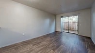 Located at 2020 Calle Lorca in Santa Fe, NM, this single-floor, one-bedroom, two-bathroom residence offers a functional and well-organized layout. Wood-look plank flooring runs throughout the home, creating a warm, cohesive aesthetic across every room.

The combined dining and living area is open and airy, featuring a textured ceiling and a full-width sliding glass door that fills the space with natural light and provides direct access to a private patio. The kitchen is outfitted with white shaker-style cabinetry, granite-look countertops, and black appliances including a gas range, dishwasher, and refrigerator. A hallway connects the main living area to the private quarters of the home.

The bedroom is generously sized, offering a large sliding-door closet for storage and a window with a view of mature trees, bringing in natural light. Two bathrooms serve the residence, one of which features an accessible tub and shower combination equipped with safety grab bars. Additional storage is provided by a second closet, and dedicated laundry and utility rooms add practical convenience. The layout is efficient and thoughtfully arranged, making excellent use of the available space throughout.