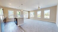 Located in Mason, Ohio, this well-appointed 2-bedroom, 2-bathroom single-story home offers a thoughtfully designed layout with modern finishes throughout. The entrance opens via a clean, neutral-toned hallway with wood-look flooring that flows naturally into the main living areas. The open-concept kitchen and living room serves as the heart of the home, featuring a large central island with a white quartz countertop and undermount sink, dark espresso cabinetry with sleek hardware, stainless steel appliances, and a classic white subway tile backsplash. Pendant lighting above the island and a ceiling fan in the living area add both style and function. Oversized windows and French doors flood the space with natural light and provide views of the surrounding greenery. Soft carpeting defines the spacious living zone. The generously sized primary bedroom enjoys multiple windows with outdoor views and a ceiling fan, accompanied by a walk-in closet with wire shelving. The second bedroom is equally well-lit with natural light. Both bathrooms are finished with wood-look tile flooring, dark vanity cabinetry, and a tub-shower combination. The home's neutral color palette and consistent finishes create a cohesive, move-in-ready atmosphere throughout.