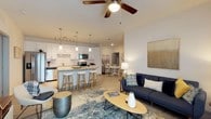 Parkside At The Beach presents a thoughtfully designed single-floor residence that blends modern finishes with a relaxed coastal aesthetic. The open-concept living and dining area is anchored by a comfortable living space with light wood-style flooring, a ceiling fan, and seamless flow into the kitchen and dining area. The kitchen is a standout feature, equipped with crisp white cabinetry, stainless steel appliances, a classic white subway tile backsplash, and a generously sized center island with pendant lighting and bar seating — ideal for casual dining or entertaining. The primary bedroom offers a serene retreat with carpeted flooring, a ceiling fan, and coastal-inspired décor. It connects to a well-organized walk-in closet with full-length hanging rods and shelving. The en-suite bathroom includes a wide vanity with white cabinetry, a large mirror, and built-in open shelving for added storage. Additional bedrooms are carpeted, naturally lit, and feature ample closet space, including walk-in options. Throughout the residence, a neutral color palette and clean lines create a bright, airy ambiance. The cohesive design and quality finishes make this space a comfortable and functional home near the beach.