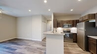 Located at 100 Grenache Blanc Dr in Saint Peters, MO, this well-designed one-bedroom, one-bathroom residence offers a thoughtful single-floor layout. The open-concept kitchen and living area forms the heart of the home, showcasing rich dark-stained cabinetry, stainless steel appliances including a range, microwave, and refrigerator, and a granite-topped peninsula with an undermount sink and sleek matte black faucet. A classic subway tile backsplash adds a polished finish to the kitchen, which flows naturally into the living area. Wood-style luxury vinyl plank flooring runs throughout the main living spaces, adding warmth and durability, while recessed lighting keeps the area bright and modern. The spacious living room features a ceiling fan and sliding glass door that invites natural light and provides outdoor access. The generously sized primary bedroom is carpeted for comfort, with a large window for natural light and a mirrored closet. The bathroom is clean and functional, featuring a full soaking tub and shower combination with updated hardware. Neutral warm-toned walls throughout create a cohesive, move-in-ready atmosphere well-suited for comfortable everyday living.