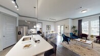 This single-floor residence showcases a thoughtfully designed open-concept layout that seamlessly connects the kitchen, dining, and living areas, creating a cohesive and functional living environment. Throughout the space, wood-style flooring, neutral gray crown molding, and crisp white walls establish a contemporary aesthetic.

The kitchen is a standout feature, equipped with gray shaker-style cabinetry, stainless steel appliances, a subway tile backsplash, and a generous island with a white quartz countertop and seating for multiple guests. Pendant lighting and a track lighting system illuminate the space effectively.

The dining area flows naturally from the kitchen and is brightened by a sliding glass door that opens to a private balcony, offering outdoor views. The living room receives ample natural light through large windows and provides a comfortable, versatile setting.

The bedroom is a well-sized retreat featuring dark hardwood-style floors, direct balcony access, multiple windows, and an ensuite bathroom. The bathroom includes a dual-sink vanity with a white countertop, gray cabinetry, a soaking tub, and wood-style flooring, delivering a clean and functional finish throughout.