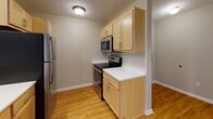 This single-floor unit offers a practical and well-organized layout with a clear separation between living, sleeping, and functional spaces. The open-concept design connects the kitchen directly to the living area, with a peninsula counter serving as a natural divider between the two zones. The kitchen is equipped with stainless steel appliances, including a refrigerator, electric range, and over-the-range microwave, complemented by light wood cabinetry and white countertops. Hardwood-style flooring runs throughout the kitchen and entry areas, while plush carpet covers the living room and bedrooms.

The living area is bright and open, with recessed lighting and a pendant light adding warmth to the space. A hallway leads to the bedrooms, each finished with soft carpet and standard windows that bring in natural light. One bedroom features dual windows with blinds and a ceiling fan with light fixture, offering views of the surrounding outdoor landscape. The bathroom includes a walk-in shower enclosed by sliding frosted glass doors with chrome hardware, a vanity with light wood cabinetry, and tile flooring. The unit's neutral color palette and clean finishes contribute to a calm, functional ambiance throughout.