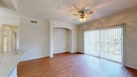 Located in Austin, TX, this single-floor, 2-bedroom, 1-bathroom residence offers a well-designed layout with thoughtful architectural details throughout. The living room serves as the heart of the home, showcasing warm wood-look flooring, crown molding, and a ceiling fan with a light fixture. A decorative arched niche adds character to the space, while a sliding glass door with vertical blinds fills the room with natural light and provides access to an outdoor area with greenery views.

The kitchen is efficiently laid out with warm wood cabinetry, stainless steel appliances including a refrigerator, range, and microwave, light stone countertops, a sink, and track lighting overhead. It connects seamlessly to the main living areas via an arched passageway.

Both bedrooms feature plush carpet, ceiling fans, and windows overlooking lush outdoor foliage. The spacious primary bedroom includes a generously sized walk-in closet outfitted with wire shelving for ample storage. The full bathroom offers a tub/shower combo with decorative tile accenting, a wood-toned vanity with stone countertop, and wood-look flooring. A hallway connects the main spaces, completing this cohesive and functional floor plan.