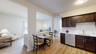 Located at 130 Slade Dr in Alden, NY, this single-floor, 2-bedroom, 1-bathroom home offers a thoughtfully designed layout with modern finishes throughout. Light wood-tone flooring runs continuously across the living spaces, lending a clean, cohesive aesthetic.

The living room is bright and welcoming, featuring large sliding glass doors that flood the space with natural light and provide direct outdoor views. The open-concept dining area and kitchen sit at the heart of the home, connected by an arched passageway. The kitchen is equipped with rich dark-wood cabinetry, marble-style countertops, stainless steel appliances including a refrigerator, range, microwave, and dishwasher — providing both style and functionality.

The spacious primary bedroom offers a generous footprint with a double-door closet, while the second bedroom provides ample space with its own closet access. Four closets throughout the home ensure plentiful storage. The bathroom features dark-wood vanity cabinetry with marble-style countertops, a well-lit mirror, and an accessibility-equipped walk-in shower with multiple grab bars. In-unit laundry adds everyday convenience. The home's neutral palette, clean lines, and practical design make it a comfortable and functional living space.