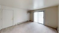 This single-floor, two-bedroom, one-bathroom unit presents a straightforward and functional layout designed to maximize everyday livability. The living area features neutral-toned carpet and a sliding glass door with vertical blinds, allowing natural light to fill the space while providing access to the outdoors. A wall-mounted air conditioning unit and baseboard heating ensure year-round comfort.

The galley-style kitchen is efficiently arranged, featuring white cabinetry with ample storage above and below the countertops, a double-basin sink, a gas range, and a full-size refrigerator. Tile flooring and under-cabinet lighting contribute to a clean, practical workspace.

Both bedrooms are carpeted and finished in neutral tones, each equipped with baseboard heating. One bedroom includes a window overlooking the exterior, while the other offers a more private feel with easy access to the shared hallway. Each room provides a blank canvas well-suited for personalization.

The bathroom is clean and simply appointed, featuring a full soaking tub with a tiled surround, a chrome shower rod, and white fixtures throughout. The overall aesthetic of the unit is understated and move-in ready, making it a practical option for those seeking a comfortable, no-frills living space.