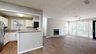 Located at 7889 Roswell Rd in Sandy Springs, GA, this single-floor residence offers a well-designed layout with a blend of practical finishes and comfortable living spaces throughout. The main living area is highlighted by rich, dark hardwood-style flooring, neutral gray walls, and a textured ceiling. Large windows and a glass-panel entry door allow generous natural light to fill the space, while a ceiling fan adds to the room's functionality. A wood-burning fireplace serves as a focal point in the open living room, creating a warm and inviting atmosphere. The kitchen is thoughtfully appointed with white cabinetry, granite countertops, and a full suite of stainless steel appliances including a gas range, over-the-range microwave, dishwasher, and refrigerator. A pass-through window connects the kitchen to the living area, enhancing the open feel of the shared space. The bedrooms feature plush carpeting, ceiling fans, and ample closet space, with at least one room offering a walk-in-style closet with built-in shelving. The bathroom is outfitted with a full tub-shower combination, hardwood-style flooring, and granite vanity detailing. The property is set among mature trees, providing a natural and serene backdrop visible from multiple windows throughout the unit.