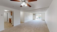 Located at 560 N Main St in Leominster, Massachusetts, this single-floor unit offers a clean, functional layout designed for comfortable everyday living. The expansive main living area is a standout feature, with soft wall-to-wall carpeting, bright white walls, and a ceiling fan with light kit overhead. A wall-mounted air conditioning unit and baseboard heating ensure year-round comfort, while sliding glass doors open to an outdoor area, allowing natural light to pour in and providing pleasant exterior views. The open layout connects seamlessly to the entryway, which features a warm wood-toned front door. The kitchen is efficiently arranged in a galley style, fitted with oak cabinetry, white appliances including an electric range, microwave, refrigerator, and dishwasher, and easy-to-maintain tile flooring. The bedroom is generously sized with plush carpeting, natural light from a window with exterior views, baseboard heating, and access to a dedicated closet with built-in shelving. The full bathroom is well-appointed with tile flooring, a combination tub and shower, a wood-framed vanity mirror, and an oak vanity cabinet with a countertop sink. Throughout the unit, a neutral color palette and straightforward design create a bright, move-in-ready environment.
