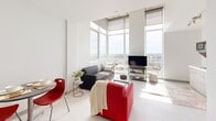 Located on the 20th floor of a modern high-rise at 20 Rebecca St in Hamilton, Ontario, this 2-bedroom, 1-bathroom unit offers an impressive blend of contemporary design and elevated urban living. The living room is the centrepiece of the unit, characterized by dramatic floor-to-ceiling windows that wrap around the corner, flooding the space with natural light and offering sweeping panoramic views of the Hamilton cityscape and beyond. Soaring ceilings amplify the sense of openness, while large-format white tile flooring runs throughout the main living area, contributing to the bright, clean aesthetic. A bold blue accent wall anchors the interior corridor, adding a touch of character to the otherwise neutral palette. Both bedrooms are private and accessed via individual doors, each featuring tall windows with city views, built-in storage cabinetry, under-bed drawer storage, a desk workspace, and comfortable carpet flooring. The bathroom is finished with white tile flooring, dark mosaic tile accents, a white vanity with an integrated sink, and a large mirror. The unit's efficient layout maximizes every square foot, making it a well-appointed and functional space in the heart of Hamilton.