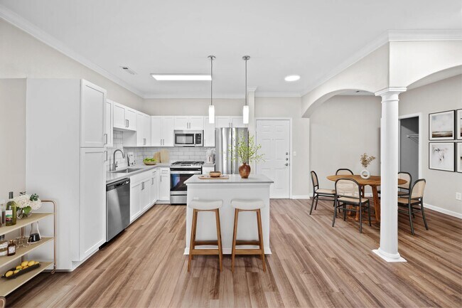 Cocina y comedor con columnas arquitectónicas, una isla espaciosa y una distribución abierta que reúne las comidas diarias y las reuniones. - The Avens at Dedham Station