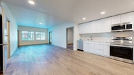 This well-appointed 4-bedroom, 2-bathroom residence at The Grandview in West Sacramento, CA offers a thoughtfully designed single-floor layout with a clean, modern aesthetic. Light-toned hardwood flooring runs throughout the entire unit, creating a cohesive and bright atmosphere across every room. The open-concept living and kitchen area forms the heart of the home, where natural light pours in through large windows fitted with blinds. The sleek kitchen is outfitted with flat-front white cabinetry extending to the ceiling, a subway tile backsplash, stainless steel appliances including a refrigerator, range, microwave, and dishwasher, and a deep undermount sink. The four bedrooms are well-proportioned and bright, each benefiting from natural light via windows with outdoor views. The primary bedroom includes direct outdoor access through a sliding glass door leading to a private balcony. Closet space is incorporated into the bedrooms, including a built-in shelving system. The two bathrooms maintain the home's modern style, featuring flat-front white vanity cabinetry with undermount sinks and white quartz countertops. One bathroom includes a full soaking tub with white subway tile surround. Recessed lighting throughout ensures consistent illumination across all living spaces.
