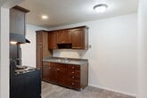Located at 2345 N Harrison Rd in East Lansing, MI, this 2-bedroom, 1-bathroom unit offers a functional and comfortable single-floor layout. The living room is a bright, open space with plush carpeting, a baseboard heating system, a wall-mounted AC unit, and a sliding glass door that opens to a private balcony with lush, tree-lined views. An adjacent dining area provides a seamless transition into the kitchen, which features rich dark-wood cabinetry, granite-style countertops, a double-basin sink, and black appliances including a range and refrigerator, set over easy-care wood-look flooring. Both bedrooms are carpeted and well-sized, with the primary bedroom offering ample space, and the second bedroom benefiting from a window with outdoor views and a baseboard heater. Two closets provide convenient storage throughout the unit. The full bathroom includes a tiled tub-shower combo with decorative accent tiles, a granite-top vanity, a large mirror, and wood-look flooring. A connecting hallway ties all rooms together efficiently. Neutral tones and textured ceilings give the unit a clean, consistent aesthetic throughout.