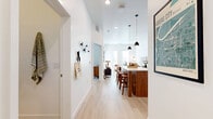 Located at 13500 Antioch Rd in Overland Park, KS, this thoughtfully designed one-bedroom, one-bathroom residence makes excellent use of its single-floor layout. A welcoming entryway with wall-mounted hooks leads into the heart of the home — an open-concept kitchen and living area bathed in natural light from large windows. The kitchen is a standout feature, showcasing warm wood cabinetry, sleek gray upper cabinets, a white quartz waterfall island with bar seating, stainless steel appliances, subway tile backsplash, and stylish black pendant lighting. Light hardwood flooring runs throughout the main living areas, lending a clean and cohesive aesthetic. The living room offers generous wall height, abundant natural light, and direct access to a private exterior door. The bedroom is a calm, carpeted retreat with a large window, soft wall sconces, and ample space for comfortable furnishings. The bathroom features rich wood vanity cabinetry with a white countertop and direct access to a dedicated walk-in closet with built-in shelving and hanging rods. An in-unit laundry area with a front-loading washer and overhead shelving completes this well-appointed residence.
