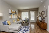 This single-story residence is thoughtfully designed with a cohesive neutral palette and quality finishes throughout. The living area serves as the heart of the home, featuring warm wood-style flooring, large windows with blinds and sheer curtains, and a glass-paned door providing direct access to the outdoors. Natural light fills the space, creating an inviting and open atmosphere.

The kitchen is well-equipped with dark espresso cabinetry extending to the ceiling, granite countertops, stainless steel appliances including a refrigerator and built-in microwave, a tile backsplash, and a peninsula island with pendant lighting and bar seating. The layout offers generous counter and storage space, with hardwood-style flooring continuing from the main living areas.

The bedrooms are carpeted and generously proportioned, with large windows admitting ample natural light. The primary bedroom includes a ceiling fan and direct access to a walk-in closet featuring multi-tiered wire shelving. The primary bathroom offers dark cabinetry, granite countertops, a wide vanity mirror, and a glass-enclosed tiled shower. A second full bathroom mirrors this refined aesthetic with similar finishes and a granite-topped vanity.