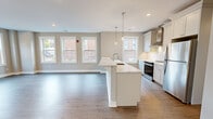 Located at 85 Martin Luther King Ave in Morristown, NJ, this thoughtfully designed 2-bedroom, 2-bathroom residence offers a bright and modern living experience across a single, well-organized floor. The open-concept kitchen and living area serves as the heart of the home, showcasing a large center island with quartz countertops, a undermount sink, and elegant pendant lighting. White shaker cabinetry, subway tile backsplash, and stainless steel appliances — including a range, dishwasher, and refrigerator — complete a sleek, functional kitchen. The living area extends naturally from the kitchen, filled with natural light from multiple large windows. Hardwood flooring flows throughout the space, tying each room together cohesively. The primary bedroom is generously proportioned, featuring multiple windows with neighborhood views and access to a well-appointed walk-in closet outfitted with custom shelving and double hanging rods. The second bedroom also benefits from abundant natural light through corner windows. Both bathrooms are finished with neutral tile, quartz vanities, and clean fixtures. A hallway connects the private quarters to the main living areas, with Shaker-style interior doors adding a refined touch throughout.
