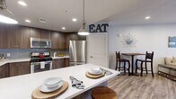 Located at 255 N 400 W in Salt Lake City, Utah, this thoughtfully designed one-bedroom, one-bathroom residence offers a functional and stylish single-floor layout. The open-concept kitchen and living area serves as the heart of the home, featuring rich dark walnut-toned cabinetry, a gray subway tile backsplash, white quartz countertops, and a full suite of stainless steel appliances including a gas range and built-in microwave. A large kitchen island with pendant lighting and bar seating provides additional prep and dining space, while a dedicated dining nook adds further versatility. The living room is bright and inviting, with recessed lighting, wood-look flooring, and direct access to an outdoor area through full-length glass doors and large windows that bring in natural light. The generously sized primary bedroom features plush carpeting, a ceiling fan, and its own private access to the outdoors. A dedicated closet offers practical storage. The bathroom is clean and modern, appointed with wood-look tile flooring, a white tiled shower-tub combination, and a warm wood vanity with quartz countertops. Throughout the residence, neutral tones and contemporary finishes create a cohesive, comfortable ambiance.