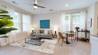 Located at 3506 Buster Lane in Indian Land, South Carolina, this single-story residence offers a thoughtfully designed open-concept layout that seamlessly connects the main living areas. Light-toned hardwood-style flooring flows throughout the common spaces, complementing the neutral color palette and creating a cohesive, contemporary aesthetic.

The living room is generously proportioned, featuring ceiling fans, recessed lighting, and multiple windows dressed with white curtains and blinds that invite abundant natural light. A private entry door provides direct outdoor access from this space. The adjoining dining area offers a comfortable spot for everyday meals or entertaining.

The kitchen stands out as a central feature, showcasing white shaker-style cabinetry, granite countertops, a subway tile backsplash, and stainless steel appliances. A large island with seating for multiple guests serves as both a functional workspace and a social hub, with pendant lighting overhead adding a polished touch.

The bedrooms are carpeted for comfort, each featuring ceiling fans, generous window placement with outdoor views, and ample space for furnishings. The bathroom is cleanly finished with white cabinetry, granite countertops, a large mirror, and light hardwood-style flooring, maintaining the consistent design language found throughout the home.