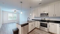 Located at 4101 Runner Lp in Chester, VA, this thoughtfully designed one-bedroom, one-bathroom residence offers a comfortable and modern living experience on a single floor. The open-concept layout seamlessly connects the kitchen and living area, creating an efficient and inviting space.

The kitchen is a standout feature, showcasing crisp white shaker-style cabinetry with matte black hardware, rich dark granite countertops, and a full suite of stainless steel appliances including a refrigerator, electric range, built-in microwave, and dishwasher. A peninsula with pendant lighting above provides additional counter space and serves as a natural divider between the kitchen and living area. Light wood-tone flooring runs throughout the main living spaces, complementing the neutral color palette.

The bedroom is carpeted for comfort and features multiple windows with blinds that invite generous natural light and views of surrounding greenery. A ceiling fan adds functionality, and a dedicated closet provides ample storage.

The bathroom is clean and well-finished, with a granite-topped vanity, light wood cabinetry, a tiled tub-shower combination, and wood-look flooring that ties the space together cohesively. The overall ambiance is bright, modern, and move-in ready.