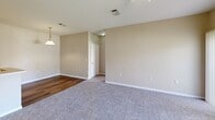 Located at 1773 Popps Ferry Rd in Biloxi, Mississippi, this single-floor, two-bedroom, one-bathroom unit offers a practical and comfortable layout. The kitchen features light wood cabinetry, a peninsula with a built-in sink, and white appliances including a refrigerator, electric range, and microwave. Hardwood-style flooring runs through the kitchen and main living areas, while neutral-toned carpet adds warmth to the living and bedroom spaces. A pendant light fixture accents the dining area, which flows openly into the living room. Both bedrooms are carpeted and equipped with ceiling fans and natural light from windows with blinds. The primary bedroom is generously sized and connects conveniently to the bathroom, which features a full tub-shower combo, toilet, vanity, and hardwood-style flooring. A dedicated laundry room includes washer/dryer hookups, built-in shelving, and hardwood-style flooring, adding everyday convenience. Two closets provide ample storage throughout the unit. Warm, neutral wall tones and white trim create a clean, cohesive aesthetic throughout this well-appointed Biloxi residence.