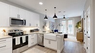 This thoughtfully designed one-bedroom, one-bathroom residence offers a cohesive open-concept floor plan that maximizes every square foot with style and function. The kitchen is a standout centerpiece, showcasing white shaker cabinetry with matte black hardware, a striking marble-look tile backsplash, quartz countertops, stainless steel appliances, and a large farmhouse sink set into a peninsula with bar seating. Three bold black pendant lights hang overhead, adding a contemporary flair. Light wood-look flooring flows seamlessly from the kitchen into the living area, which is bright and welcoming with a ceiling fan, neutral tones, and French doors that open to an outdoor view, filling the space with natural light. The bedroom is carpeted for comfort, features a ceiling fan, and is illuminated by a window with curtains. It connects directly to a well-organized walk-in closet with built-in shelving and hanging rods. The bathroom is clean and modern, with a white vanity, quartz countertop, a framed mirror with black accents, tile flooring, and a tub-shower combo with subway tile surround. A dedicated closet with direct bathroom access adds practical convenience throughout this refined, move-in-ready residence.