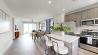 This two-story home is designed for comfortable, modern living across two well-proportioned floors. The main level centers on an open-concept living, dining, and kitchen area bathed in natural light from large sliding glass doors that open to the outdoors. The kitchen is a standout feature, equipped with taupe shaker-style cabinetry, stainless steel appliances, a subway tile backsplash, and a central island with a quartz countertop and bar seating — ideal for casual dining or entertaining. The adjoining dining and living areas flow seamlessly, finished with light hardwood-style flooring, recessed lighting, and a ceiling fan that enhances the bright, airy atmosphere.

Upstairs, three bedrooms provide comfortable retreats, including a generously sized primary bedroom with a dedicated walk-in closet. The primary bathroom is well-appointed with both a soaking tub and a separate glass-enclosed shower, complemented by clean white finishes and light wood flooring. The additional bedrooms are bright and versatile, each with natural light and easy access to the remaining bathrooms. A dedicated laundry room with full-size washer and dryer adds everyday convenience. Throughout, the home maintains a cohesive, clean aesthetic with neutral tones and contemporary finishes.