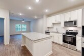 Located at 2465 Richardson Pkwy in Jonesboro, GA, this well-appointed one-bedroom, one-bathroom residence offers a thoughtfully designed layout across a single floor. The open-concept kitchen and living area serves as the heart of the home, anchored by a large granite-topped island that provides ample prep and dining space. The kitchen is outfitted with crisp white shaker cabinets, a classic subway tile backsplash, stainless steel appliances including a range, microwave, and refrigerator, and a stainless steel sink. Wood-look flooring flows throughout the entire residence, lending warmth and visual continuity. Recessed lighting illuminates the kitchen and living area, which also features a ceiling fan and multiple windows that invite abundant natural light and views of surrounding greenery. The bedroom is a comfortable, well-lit retreat with dual windows overlooking lush trees and its own ceiling fan. The bathroom is finished with granite countertops, a tiled tub-shower combination, and accessible grab bars. A dedicated laundry room with full-size washer and dryer hookups adds everyday convenience. A separate closet provides additional storage. The residence is completed by a smart thermostat and a clean, neutral color palette throughout.