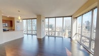 Located in the heart of Chicago at 310 S Canal Street, this high-rise residence offers an impressive living experience defined by panoramic city skyline views and contemporary design. The expansive open-concept living area is anchored by floor-to-ceiling windows on multiple walls, flooding the space with abundant natural light and framing striking views of Chicago's iconic skyline. Rich, dark hardwood flooring runs throughout the main living areas, adding warmth and elegance to the open layout. A balcony door provides direct outdoor access, further connecting the interior to the dramatic urban backdrop. The galley-style kitchen is well-appointed with warm wood cabinetry, granite countertops, stainless steel appliances including a range, microwave, and refrigerator, and its own window overlooking the city. The bedroom features plush carpeting and a large floor-to-ceiling window with sweeping views of surrounding high-rises. Two bathrooms serve the residence: a full bath with tile surround tub and shower combination, and a spacious primary bath complete with a double vanity, separate glass-enclosed shower, and soaking tub, all finished in neutral tones with tile flooring. The overall ambiance is sleek and modern, ideal for experiencing urban Chicago living at elevation.
