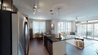 This well-appointed 2-bedroom, 2-bathroom residence in Spring, Texas is designed with an open-concept layout that seamlessly connects the kitchen, dining, and living areas. Rich dark hardwood flooring runs throughout the main living spaces, complementing the warm, neutral color palette.

The kitchen is a standout feature, boasting dark granite countertops, rich espresso-toned cabinetry, stainless steel appliances, and a curved island with pendant lighting — ideal for both cooking and casual dining. An adjacent dining area provides additional space for entertaining.

The living room is bright and inviting, with large windows and sliding glass doors leading to a private balcony, flooding the space with natural light. A ceiling fan adds comfort to the airy atmosphere.

Both bedrooms are generously sized with plush carpeting, large windows with exterior views, and ceiling fans. Each bedroom benefits from dedicated closet space, including a walk-in closet. The bathrooms feature dark granite vanities, rich wood cabinetry, and modern fixtures.

A welcoming entryway with a built-in display niche and decorative wall accents adds a thoughtful design touch. The unit's single-floor layout ensures convenient, accessible living throughout.