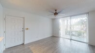 Located at 9051 SW 122nd Ave in Miami, FL, this single-floor residence offers a clean, modern aesthetic throughout. The open living area is finished with light wood-tone laminate flooring that runs consistently through the space, complemented by crisp white walls and a textured ceiling. A ceiling fan with integrated lighting provides comfort and airflow, while floor-to-ceiling vertical blinds frame a large sliding glass door that fills the room with natural light and offers views of the surrounding greenery.

The galley-style kitchen is efficiently designed with white shaker cabinetry, white quartz countertops, and a classic subway tile backsplash. Stainless steel appliances — including a range, microwave, and refrigerator — provide a polished, contemporary finish. A pass-through window connects the kitchen to the living area, enhancing the sense of openness.

The bedroom is generously proportioned, featuring its own ceiling fan, a large window that invites natural light, and an expansive wall of louvered bifold closet doors offering substantial storage. The bathroom is bright and functional, with white cabinetry, quartz countertops, and a full tub-shower combination. Throughout the unit, consistent flooring and a neutral color palette create a cohesive, move-in-ready environment.