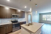 Located at 5300 Centre on Mexico Road in Saint Peters, Missouri, this well-appointed 2-bedroom, 2-bathroom residence offers a thoughtfully designed single-floor layout with modern finishes throughout. The open-concept kitchen and living area serves as the heart of the home, showcasing rich dark-wood cabinetry, a tile backsplash, light quartz countertops, and a full suite of stainless steel appliances including a refrigerator, range, and built-in microwave. A center island with a double-basin sink and elegant pendant lighting adds both functionality and style, while wood-look flooring extends through the main living areas. The living room benefits from natural light through large windows and provides access to an outdoor area via a sliding door. Both bedrooms are carpeted and feature windows that invite natural light, with the primary bedroom offering a ceiling fan for added comfort. The bathrooms are finished with dark wood vanities, neutral countertops, wood-look flooring, and a glass-enclosed shower. Additional features include a walk-in closet with wire shelving and two dedicated laundry areas, rounding out a practical and attractive living space.
