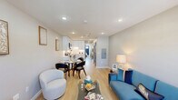 Located at 1060 Main St in South Windsor, CT, this thoughtfully designed one-bedroom, one-bathroom unit maximizes every inch of its compact footprint. The open-concept living area welcomes you through a bold navy blue entry door, which also serves as a striking design accent throughout the unit. Light wood-tone flooring runs throughout, creating a warm and cohesive aesthetic.

The living room offers a comfortable, well-lit space with recessed lighting, a wall-mounted mini-split HVAC unit, and natural light streaming through front-facing windows. It flows seamlessly into a dedicated dining area and an efficiently arranged kitchen. The kitchen is outfitted with white shaker-style cabinetry, a classic subway tile backsplash, light stone countertops, and a full suite of stainless steel appliances including a range, over-the-range microwave, and dishwasher.

The bedroom is a calm, neutral retreat featuring recessed lighting, a wall-mounted mini-split unit, and a private exterior door with a window offering neighborhood views. The bathroom showcases large-format tile, a wood-accented floating vanity, and a mirrored medicine cabinet. A hallway conveniently houses a stacked washer and dryer alongside a full-size refrigerator, maximizing functional storage and utility within the space.