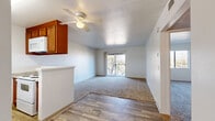 Located at 855 E River Rd in Tucson, Arizona, this one-bedroom, one-bathroom residence offers a practical and comfortable single-floor layout. The combined kitchen and living area forms the heart of the home, where wood-look hard flooring transitions seamlessly from the kitchen into the carpeted living space. The kitchen is equipped with warm-toned wood cabinetry, granite-style countertops, a double stainless steel sink, and white appliances including a refrigerator and dishwasher. A peninsula counter provides added workspace and separation between the kitchen and living area. A ceiling fan overhead and a sliding glass door leading to a private balcony with outdoor views make the living area bright and well-ventilated. The spacious bedroom features plush carpeting, a large window that brings in natural light with views of surrounding greenery, and direct access to a dedicated closet. The full bathroom is finished with wood-look flooring, a granite-top vanity with an undermount sink, a mirror, and a tiled shower-tub combination. A hallway connects the main living spaces efficiently, completing this well-organized and move-in-ready Tucson residence.