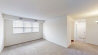 Located at 260 Christiana Rd in New Castle, Delaware, this single-floor residence offers a practical and efficiently arranged layout with two bedrooms, one bathroom, a living room, and a kitchen. The interior is finished throughout with neutral-toned carpeting in the living and bedroom areas, creating a clean and cohesive aesthetic. White walls and standard ceilings contribute to a bright, open feel throughout the unit.

The living room is a well-proportioned space featuring a wide window fitted with horizontal blinds, allowing natural light to filter in. The primary bedroom is notably spacious, with windows on multiple walls that bring in additional daylight and provide ventilation. A closet with sliding doors adds practical storage. The second bedroom is more compact but equally functional, also featuring carpeted flooring and a closet with sliding doors.

The galley-style kitchen is lined with light wood cabinetry, laminate countertops, and hardwood-style flooring. It is equipped with white appliances including a refrigerator, electric range, and an under-cabinet vent hood, along with a window above the sink. The bathroom features hardwood-style flooring, a light wood vanity with a single sink, a wall-mounted mirror, and a combined tub and shower.