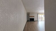 This single-floor residence offers a thoughtfully designed layout with a blend of comfort and functionality. The expansive open-plan living and dining area is a central highlight, featuring light wood-look flooring, a textured ceiling, and a classic fireplace with a wood mantel as a focal point. Built-in shelving adds practical storage and character to the space. Sliding glass doors lead out to a private balcony, allowing natural light to fill the room. Adjacent to the living area, the galley-style kitchen is efficiently laid out with dark cabinetry, light quartz countertops, a stainless steel sink, and modern appliances including a refrigerator. A peninsula counter provides a natural boundary between the kitchen and living space. The bedrooms are carpeted for comfort and each includes a ceiling fan and natural light from windows. Large closets with multi-rail storage systems offer generous organizational capacity. One bedroom features direct access to a bathroom, enhancing privacy and convenience. The bathroom is finished with white subway tile surrounding the soaking tub and shower, complemented by a light quartz vanity top and wood-toned cabinetry, creating a clean and contemporary feel throughout.