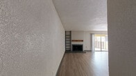 This single-floor residence offers a thoughtfully designed layout with a blend of comfort and functionality. The expansive open-plan living and dining area is a central highlight, featuring light wood-look flooring, a textured ceiling, and a classic fireplace with a wood mantel as a focal point. Built-in shelving adds practical storage and character to the space. Sliding glass doors lead out to a private balcony, allowing natural light to fill the room. Adjacent to the living area, the galley-style kitchen is efficiently laid out with dark cabinetry, light quartz countertops, a stainless steel sink, and modern appliances including a refrigerator. A peninsula counter provides a natural boundary between the kitchen and living space. The bedrooms are carpeted for comfort and each includes a ceiling fan and natural light from windows. Large closets with multi-rail storage systems offer generous organizational capacity. One bedroom features direct access to a bathroom, enhancing privacy and convenience. The bathroom is finished with white subway tile surrounding the soaking tub and shower, complemented by a light quartz vanity top and wood-toned cabinetry, creating a clean and contemporary feel throughout.