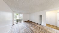 Located at 145-149 Canyon Dr in Oceanside, this well-appointed one-bedroom, one-bathroom unit offers a functional and comfortable single-floor layout. The living room is bright and open, featuring wood-style laminate flooring, a textured ceiling, and a large sliding glass door that invites natural light and provides views of the surrounding greenery. A wall-mounted heater unit is conveniently positioned in the living area. The kitchen is laid out in a galley style with crisp white cabinetry, stone-look countertops, a double-basin sink, and stainless steel appliances including a gas range and refrigerator, complemented by a dishwasher and a window for natural light. The bedroom is a comfortable, well-proportioned space finished with plush carpeting, a ceiling fan with light fixture, and a sliding window with vertical blinds for light control. The full bathroom is clean and functional, featuring a tub-shower combination, a toilet, and a vanity with a stone-style countertop, all finished with wood-style flooring consistent with the rest of the unit. A dedicated closet and hallway complete the layout, offering practical storage and easy flow throughout the space.