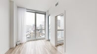 Located in the heart of downtown Montréal on Rue Stanley, this 2-bedroom, 1-bathroom unit offers a well-designed layout with a clean, modern aesthetic throughout. Light wood laminate flooring runs continuously across the entire space, complementing the crisp white walls and creating a bright, cohesive feel.

The living area provides an open, functional space filled with natural light. The kitchen is integrated into the main living area and includes built-in appliances. Both bedrooms feature floor-to-ceiling windows that frame sweeping views of the Montréal skyline, flooding the rooms with natural light. Each bedroom is equipped with a closet offering wire shelving for organized storage.

The bathroom is finished with large-format neutral tiles, a wall-mounted toilet, a glass-enclosed walk-in shower with a rain showerhead, and a vanity topped with a dark granite countertop, delivering a refined and contemporary look. A dedicated in-unit laundry area houses a stacked Electrolux washer and dryer, adding everyday convenience. A hallway connects the rooms efficiently, completing this thoughtfully arranged urban residence ideal for those seeking modern city living in one of Montréal's most vibrant neighborhoods.