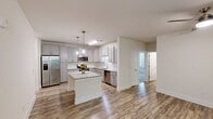 Located at 514 Pleasant Drive in Durham, NC, this thoughtfully designed single-story home offers three bedrooms, three bathrooms, and a well-appointed open layout. The kitchen serves as a centerpiece of the home, featuring granite countertops, a central island with pendant lighting, gray shaker-style cabinetry, a classic subway tile backsplash, and a full suite of stainless steel appliances. Hardwood-style flooring flows throughout the main living and dining areas, complemented by natural light streaming through large windows with views of surrounding greenery. The dining area includes a stylish chandelier and direct access to the outdoors through a glass-panel door. The primary bedroom is generously sized, carpeted for comfort, and includes a walk-in closet with wire shelving. The en-suite primary bathroom is well-equipped with a dual-sink vanity topped with granite, framed mirrors, brushed nickel fixtures, and a separate glass-enclosed shower. Additional bedrooms are carpeted and feature ceiling fans and ample natural light. Walk-in closet storage is available throughout. The home's neutral color palette and modern finishes create a clean, cohesive aesthetic throughout.
