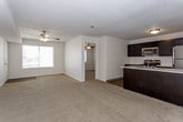 This single-floor unit offers a practical and well-organized layout designed for comfortable everyday living. The open-concept living area flows seamlessly into the kitchen, with plush, neutral-toned carpet underfoot and a textured ceiling overhead. Ceiling fans are present throughout, providing both light and airflow to the main living spaces and bedrooms.

The kitchen is a standout feature, equipped with dark espresso cabinetry that extends to the upper walls for generous storage. A full suite of stainless steel appliances includes a gas range, built-in microwave, dishwasher, and refrigerator. Light-toned countertops provide a crisp contrast to the dark cabinetry, and a peninsula with an integrated sink adds both workspace and a natural dividing point between the kitchen and living area. Wood-look flooring runs throughout the kitchen and connecting areas.

The bedrooms are carpeted and comfortably sized, each featuring a ceiling fan with light fixture and windows fitted with blinds that allow for natural light. The layout, as seen in the 3D model, shows a thoughtful arrangement that separates living and sleeping areas.

A full bathroom includes a clean, white tub and shower combination with a built-in grab bar and chrome fixtures. An in-unit laundry area accommodates a full-size washer and dryer, adding everyday convenience.