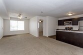 This single-floor unit offers a practical and well-organized layout designed for comfortable everyday living. The open-concept living area flows seamlessly into the kitchen, with plush, neutral-toned carpet underfoot and a textured ceiling overhead. Ceiling fans are present throughout, providing both light and airflow to the main living spaces and bedrooms.

The kitchen is a standout feature, equipped with dark espresso cabinetry that extends to the upper walls for generous storage. A full suite of stainless steel appliances includes a gas range, built-in microwave, dishwasher, and refrigerator. Light-toned countertops provide a crisp contrast to the dark cabinetry, and a peninsula with an integrated sink adds both workspace and a natural dividing point between the kitchen and living area. Wood-look flooring runs throughout the kitchen and connecting areas.

The bedrooms are carpeted and comfortably sized, each featuring a ceiling fan with light fixture and windows fitted with blinds that allow for natural light. The layout, as seen in the 3D model, shows a thoughtful arrangement that separates living and sleeping areas.

A full bathroom includes a clean, white tub and shower combination with a built-in grab bar and chrome fixtures. An in-unit laundry area accommodates a full-size washer and dryer, adding everyday convenience.